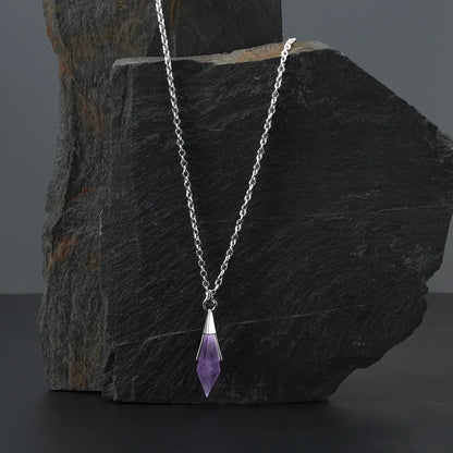 Silver-tone Prism Apex Necklace with a purple crystal pendant displayed against a dark stone backdrop.
