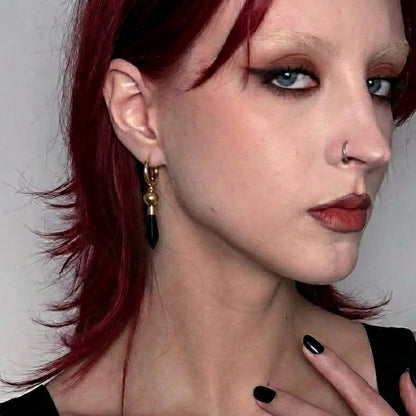Model wearing the gold Prism Orb Earrings with black crystal drops, orb bead details, and alternative gothic styling.