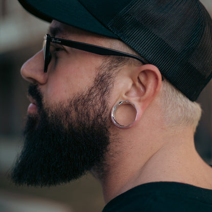 Model wearing a silver Prismatic Harmony tunnel in a stretched lobe