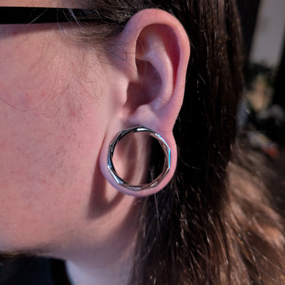 Close-up of silver Prismatic Harmony tunnel worn in a stretched lobe