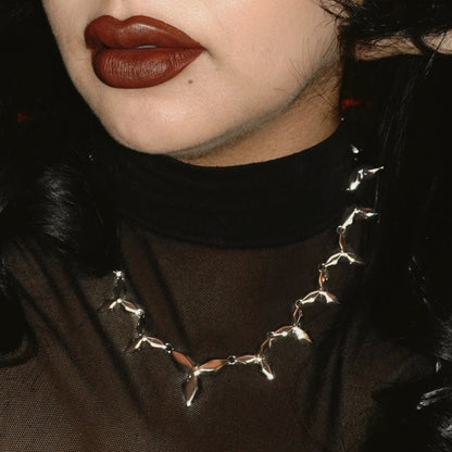 Punk petal necklace in silver, worn by model in a close-up view, featuring pointed floral links and a punk-inspired look
