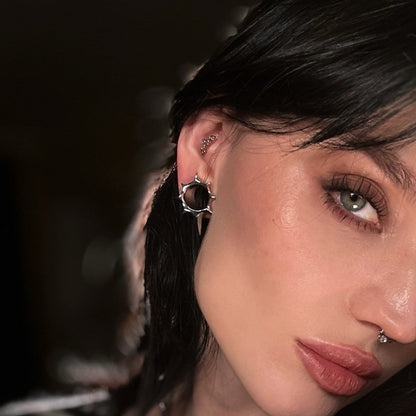 Close-up of a model's ear with a silver-tone star tunnel earring alongside multiple cartilage piercings