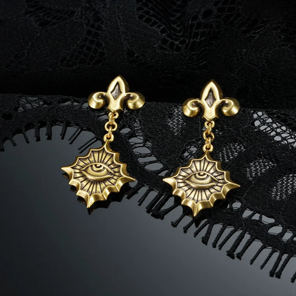 Gold-tone Radiant Witness Drop Earrings displayed as a pair against black lace on a dark reflective surface.