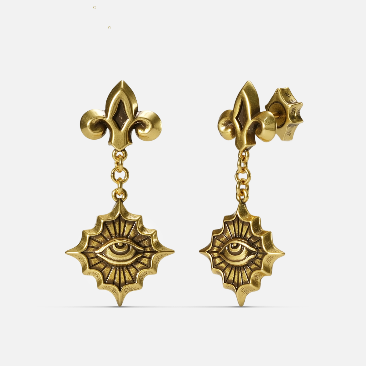 Gold-tone Radiant Witness Drop Earrings shown from front and side views with sculpted eye centers and radiating pointed frames.