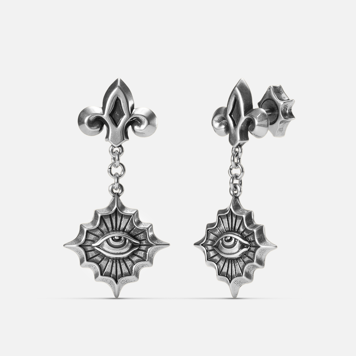 Antiqued silver-tone Radiant Witness Drop Earrings shown from front and side views with sculpted eye motifs, radiating pointed frames, and fleur-de-lis studs.