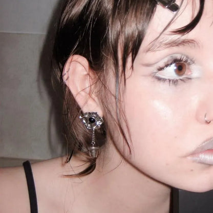 Side view of a model wearing the silver Relic Bloom Ear Studs, showing the dark floral stud, chain drop, and vessel charm detail.