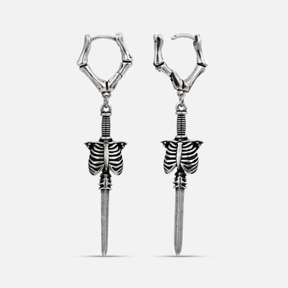 Silver-tone bone hoop earrings with dangling ribcage and blade charms on white background