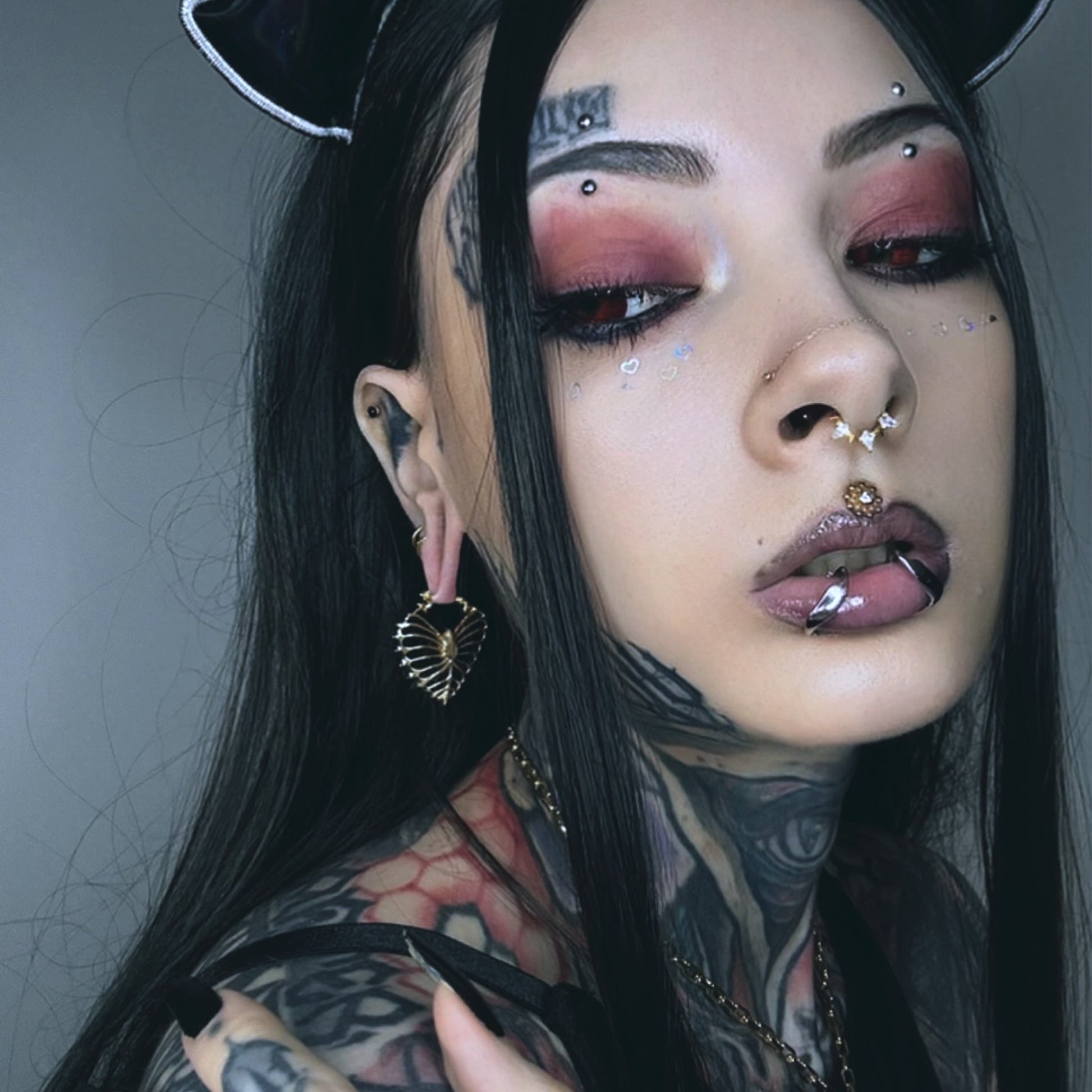 Model wearing a gold Ribheart earring with a heart-shaped rib cage design