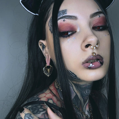 Model wearing a gold Ribheart earring with a heart-shaped rib cage design