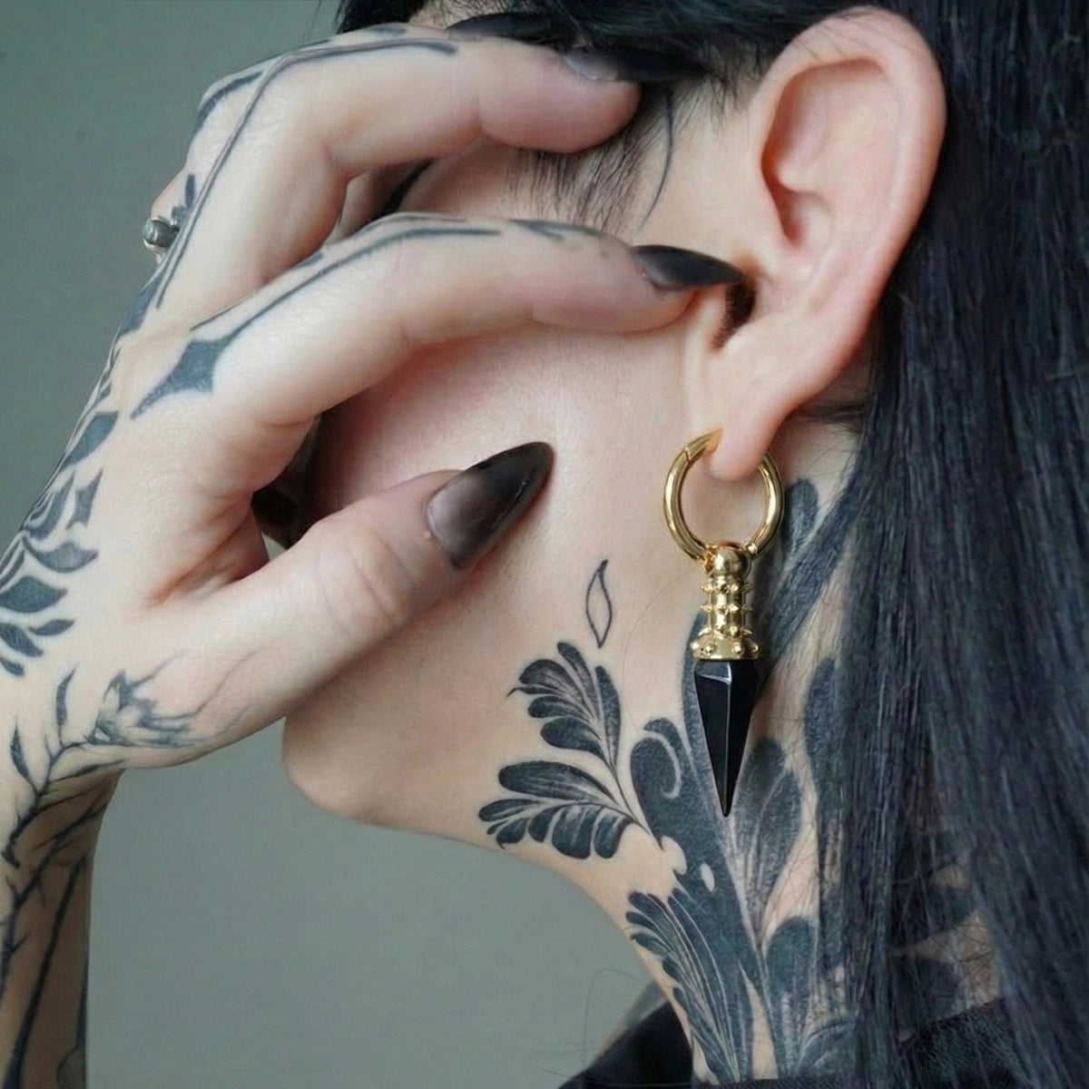 Model wearing the gold Rivet Prism Earrings with black crystal spikes, studded collar details, and bold industrial gothic styling.