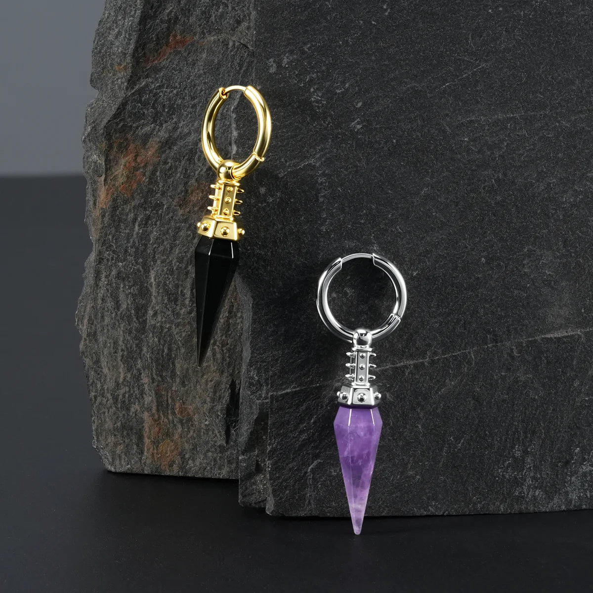 Silver and gold Rivet Prism Earrings displayed on a dark stone surface, showing faceted crystal spikes, studded collars, and industrial prism styling.