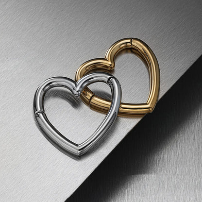 Gold-tone and silver-tone heart-shaped ear weights overlapping on a reflective surface