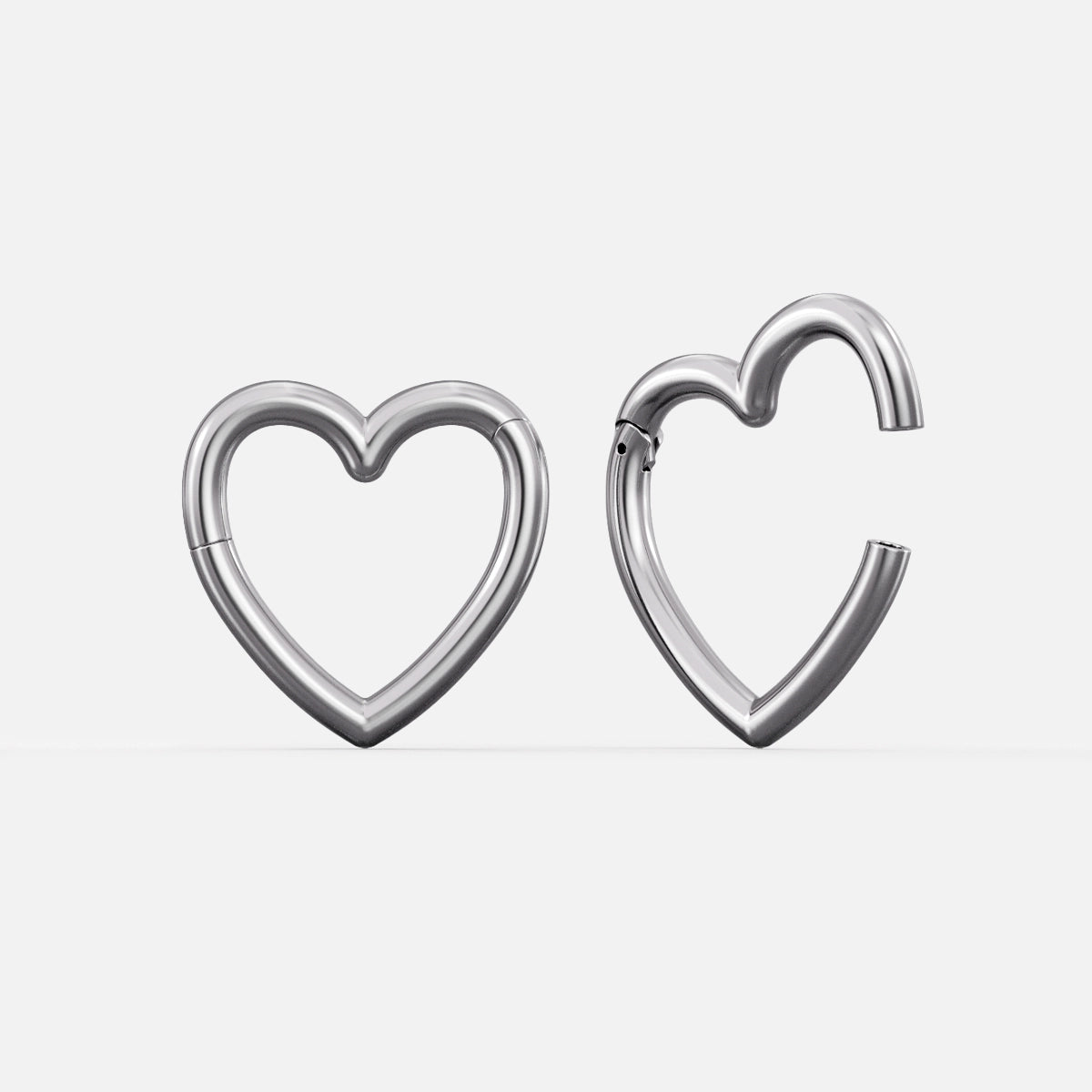 Silver-tone heart-shaped hinged ear weights, one closed and one open showing the clasp