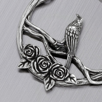 Close-up of silver Rosebird hoop earring with perched bird and sculpted roses