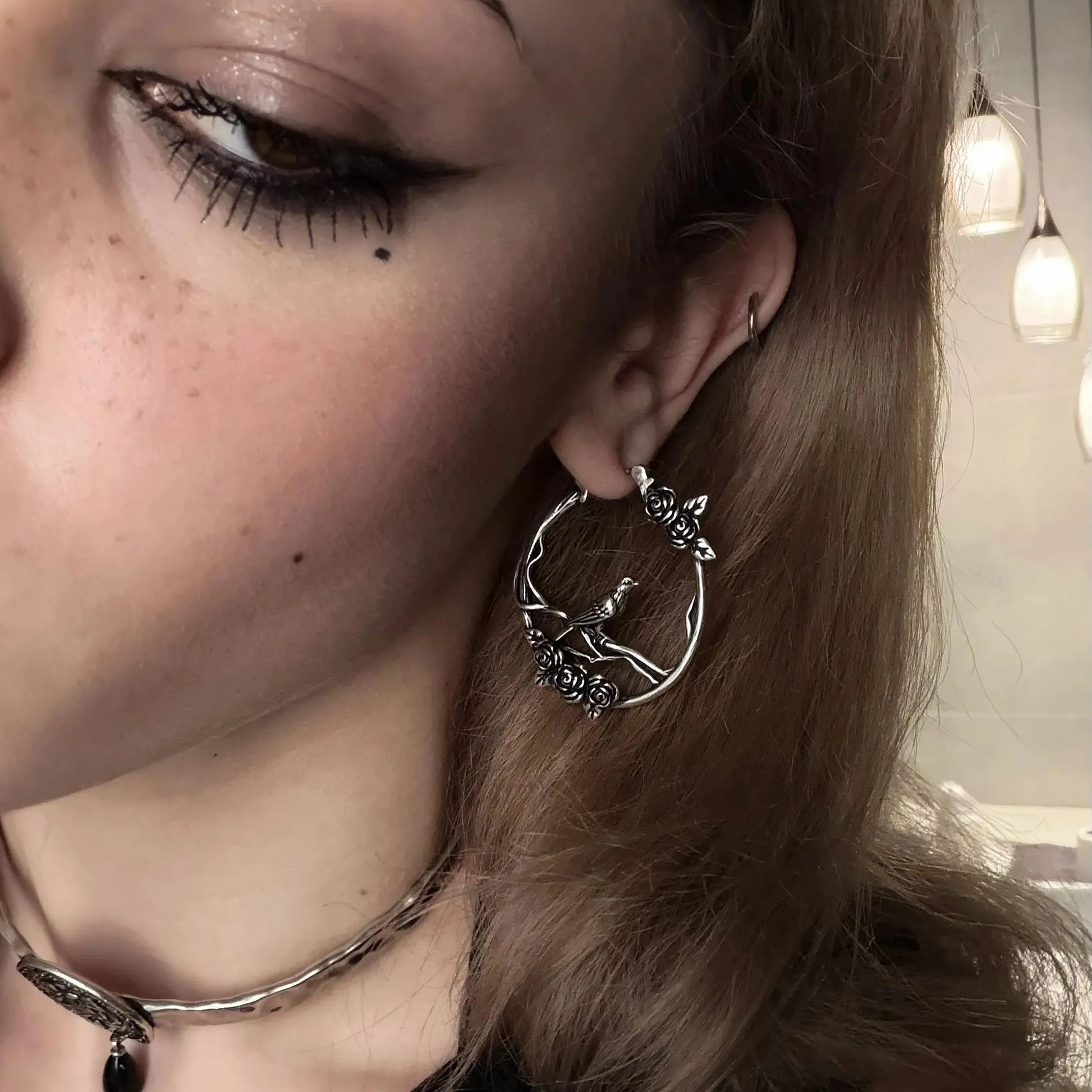 Silver Rosebird Hoop Earrings styled on model with bird, rose, and vine details in a vintage gothic jewelry look
