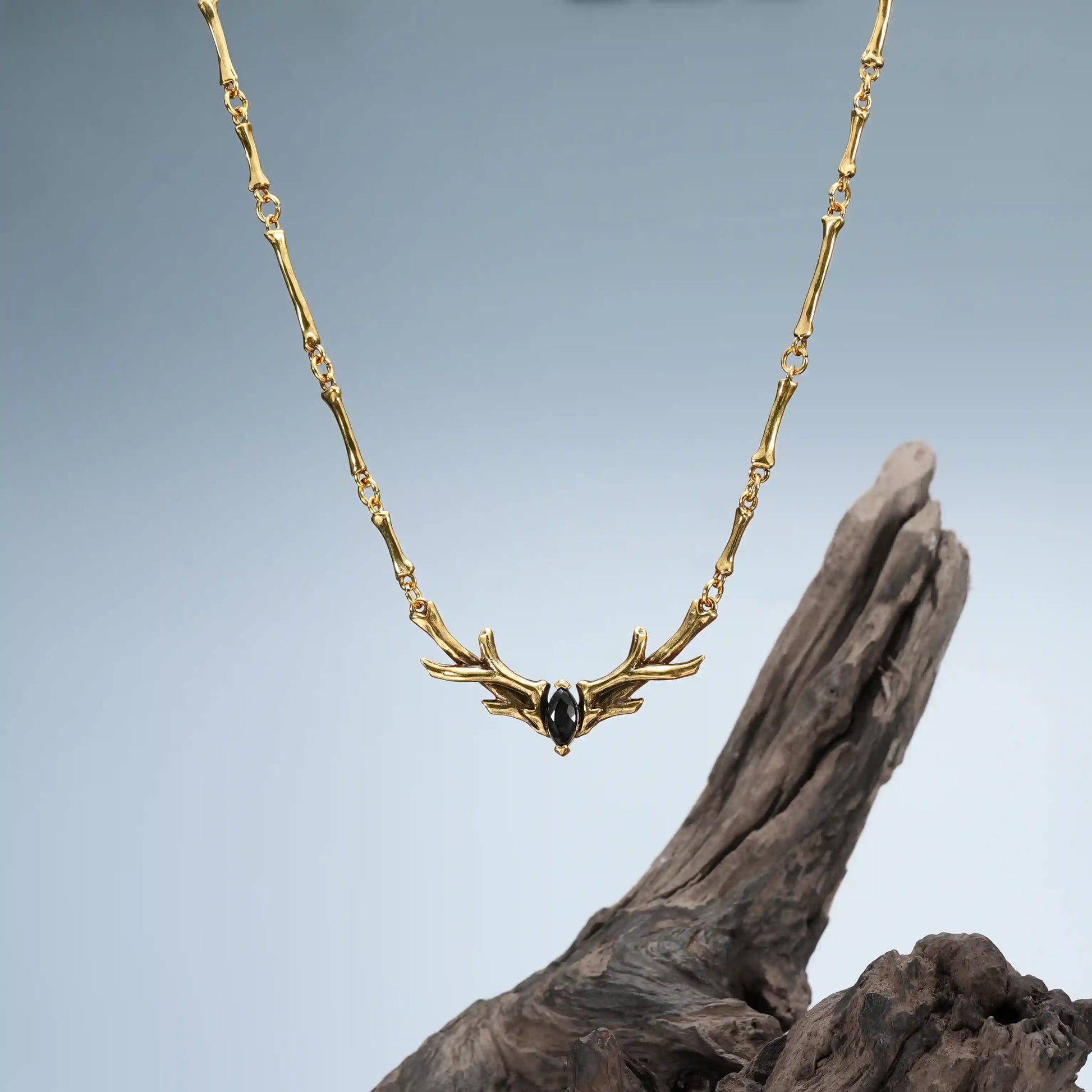 Gold Sacred Antler Collar Necklace displayed on driftwood with dark woodland jewelry styling