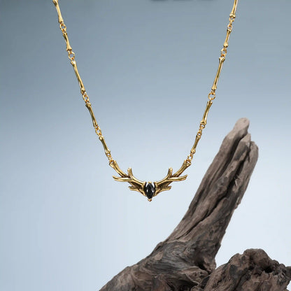 Gold Sacred Antler Collar Necklace displayed on driftwood with dark woodland jewelry styling
