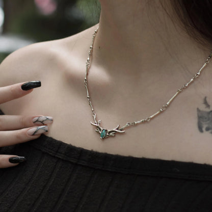 Model wearing the silver Sacred Antler Collar Necklace with turquoise centerpiece, antler-shaped design, and bone-inspired chain details.