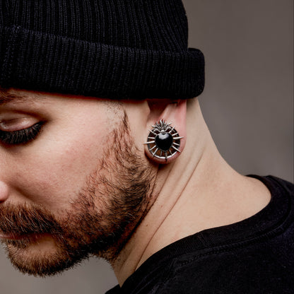 Close-up of silver Sacred Flame Heart tunnel worn below a black beanie