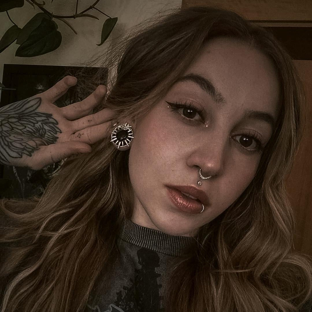 Model with wavy hair wearing a silver-tone sunburst stud earring featuring a dark heart shaped center