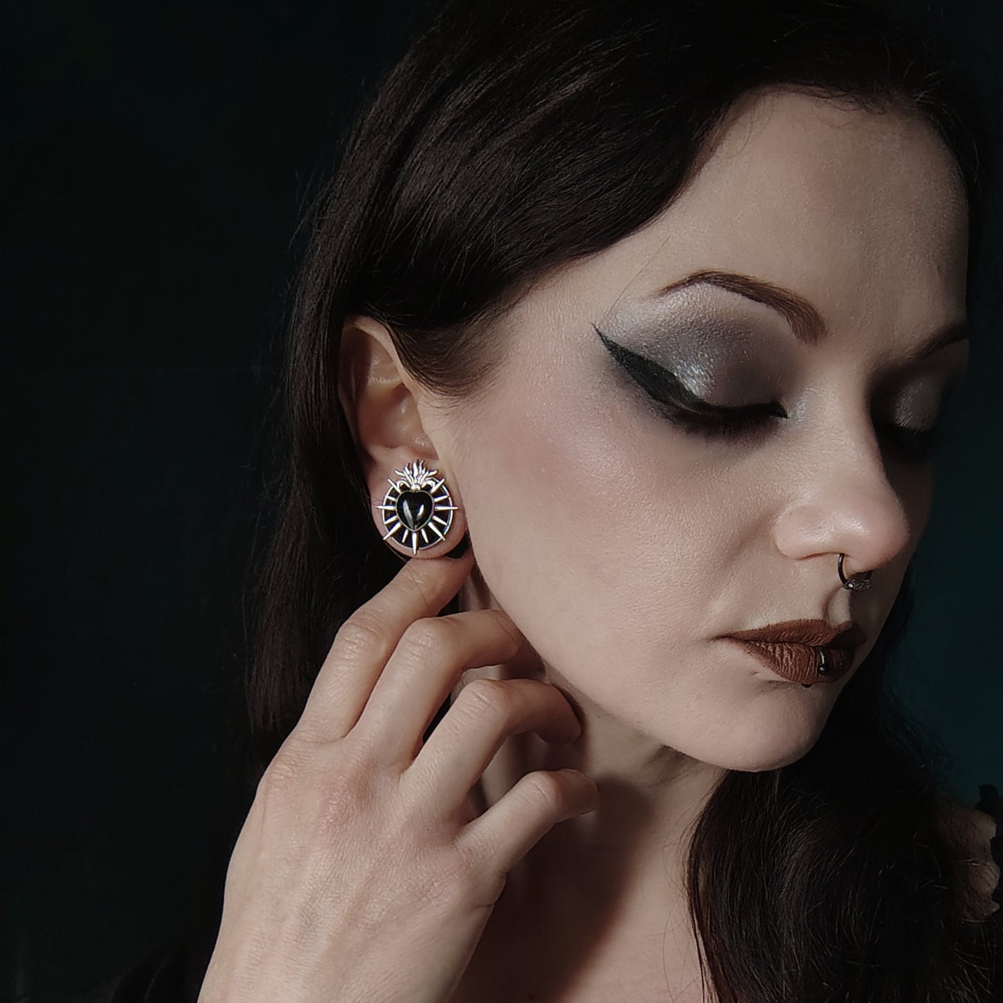 Model wearing a silver-tone heart tunnel stud earring with radiating flame details, close up profile view
