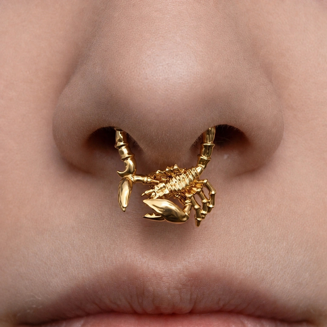 Gold-tone Scorpion Empowerment Clicker worn as a septum ring, showing its bold three-dimensional scorpion motif.