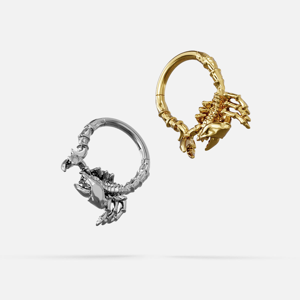 Silver- and gold-tone Scorpion Empowerment Clickers displayed together from angled views to show the sculpted details.