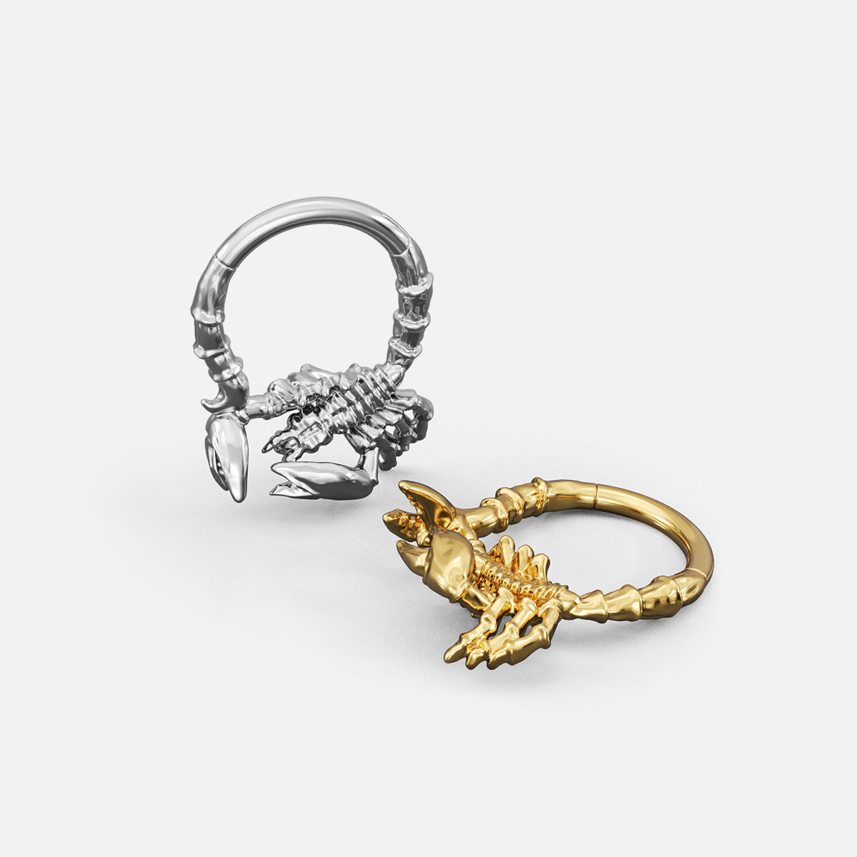Silver- and gold-tone Scorpion Empowerment Clickers shown from multiple angles to display the ring profile and scorpion motif.