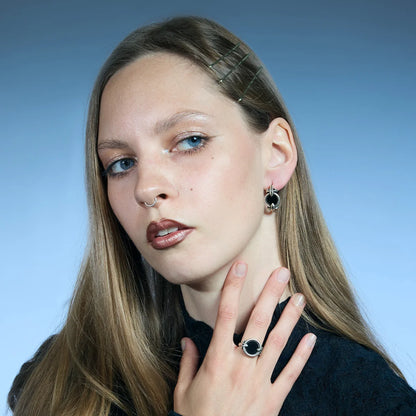 Antiqued silver-tone Scrying Mirror Hoop Earring worn in a styled portrait with the black obsidian detail facing forward.