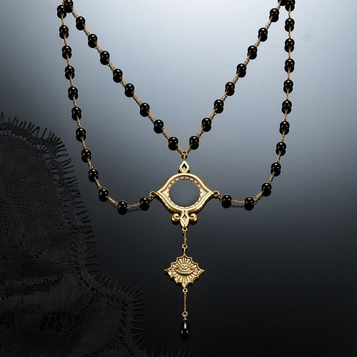 Gold-tone Scrying Mirror Necklace displayed against black lace on a dark reflective surface.