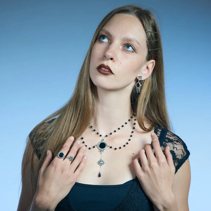 Front portrait showing an antiqued silver-tone Scrying Mirror Necklace framed across the collarbone by doubled black bead chains.