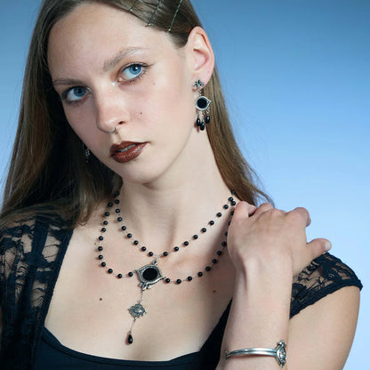 Three-quarter portrait showing an antiqued silver-tone Scrying Mirror Necklace with a black obsidian centerpiece and elongated drop.
