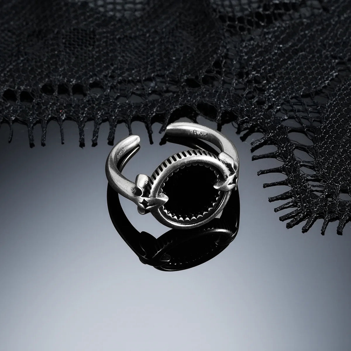Antiqued silver Scrying Mirror Ring displayed from the front on a dark reflective surface beneath black lace.