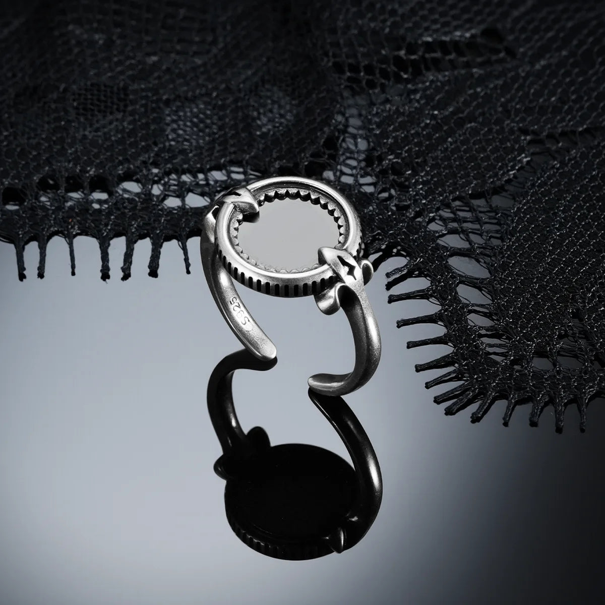 Antiqued silver Scrying Mirror Ring displayed from the side on a dark reflective surface, showing the open band and raised setting.