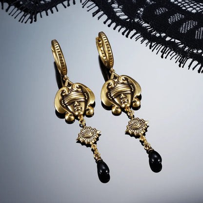 Gold-tone Second Sight Drop Earrings displayed as a pair against black lace on a dark reflective surface.