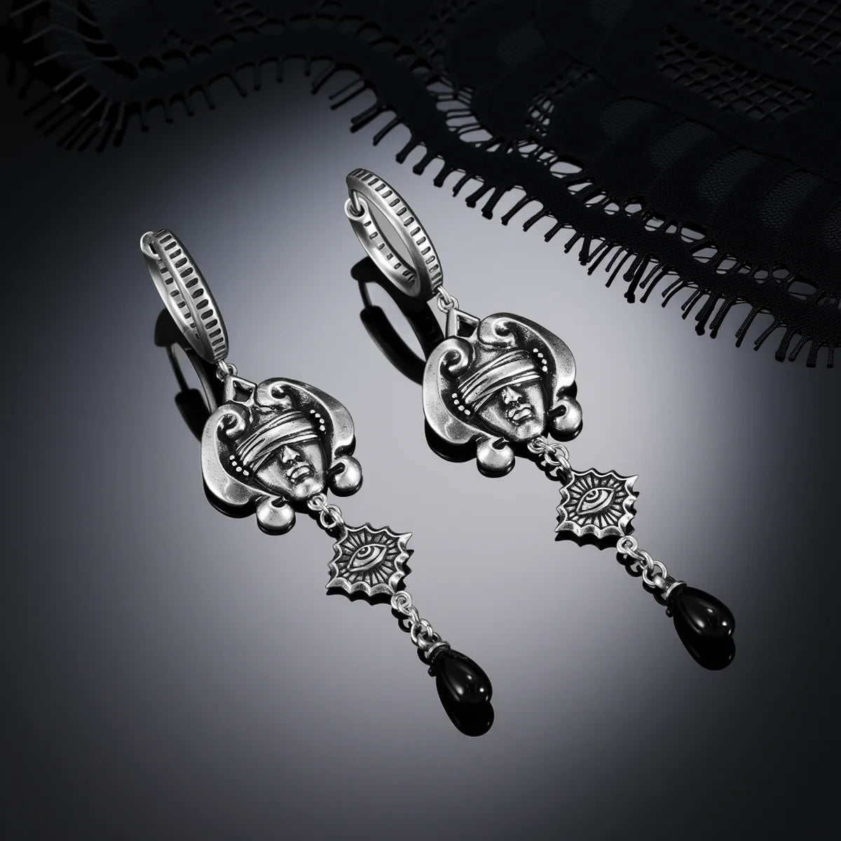 Antiqued silver-tone Second Sight Drop Earrings displayed as a pair against black lace on a dark reflective surface.