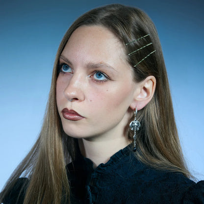 Front portrait showing a pair of antiqued silver-tone Second Sight Drop Earrings with blindfolded face and radiant eye motifs.
