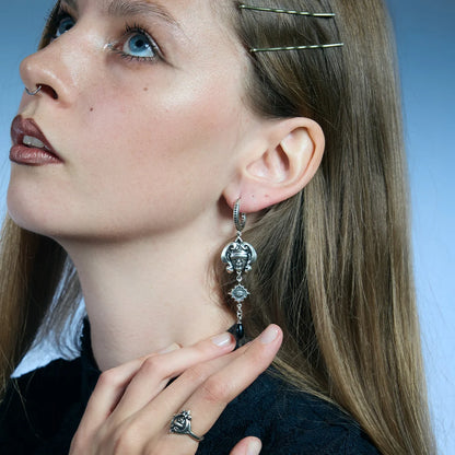 Low-angle portrait showing antiqued silver-tone Second Sight Drop Earrings hanging along the jawline.