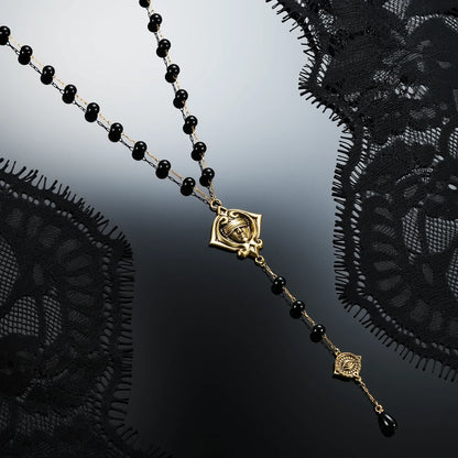 Gold-tone Second Sight Lariat Necklace displayed diagonally against black lace on a dark reflective surface.