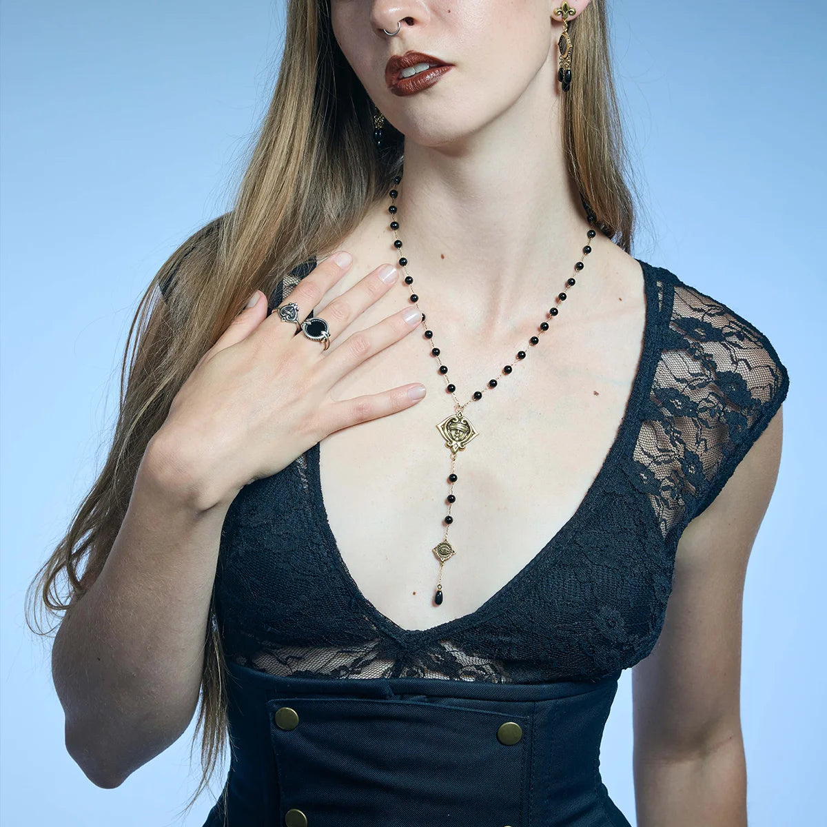Gold-tone Second Sight Lariat Necklace worn in a styled portrait with one hand resting near the long central drop.