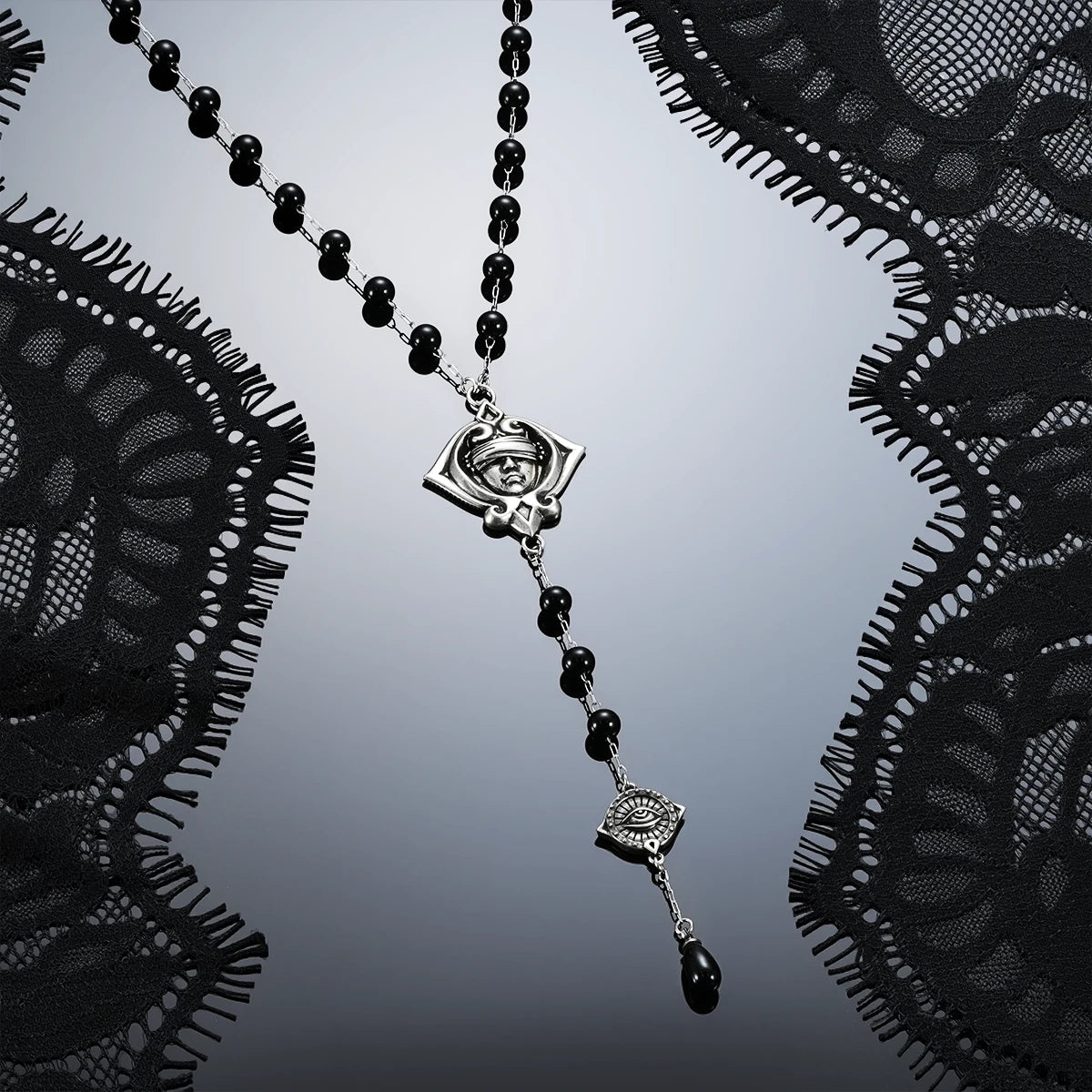 Antiqued silver-tone Second Sight Lariat Necklace displayed diagonally against black lace on a dark reflective surface.