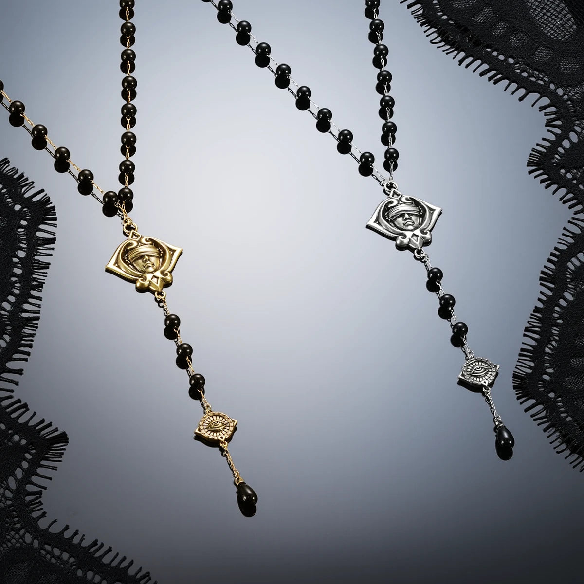 Antiqued silver- and gold-tone Second Sight Lariat Necklaces displayed together against black lace on a reflective surface.