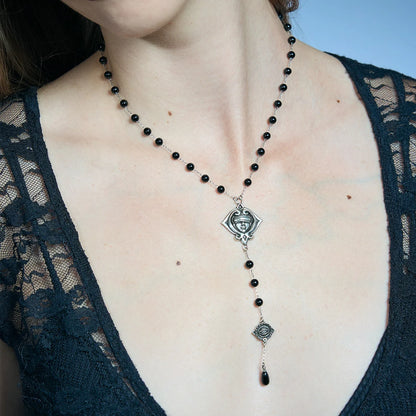Close-up of an antiqued silver-tone Second Sight Lariat Necklace worn at the chest with black beads and a long vertical drop.