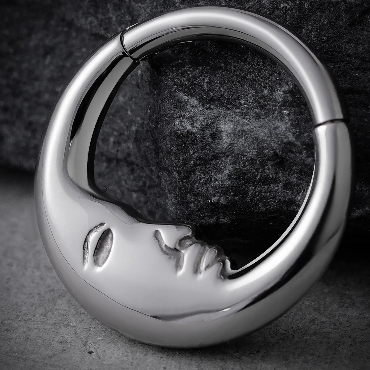 Close-up of silver Serene Face titanium clicker on dark stone