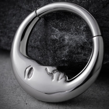 Close-up of silver Serene Face titanium clicker on dark stone