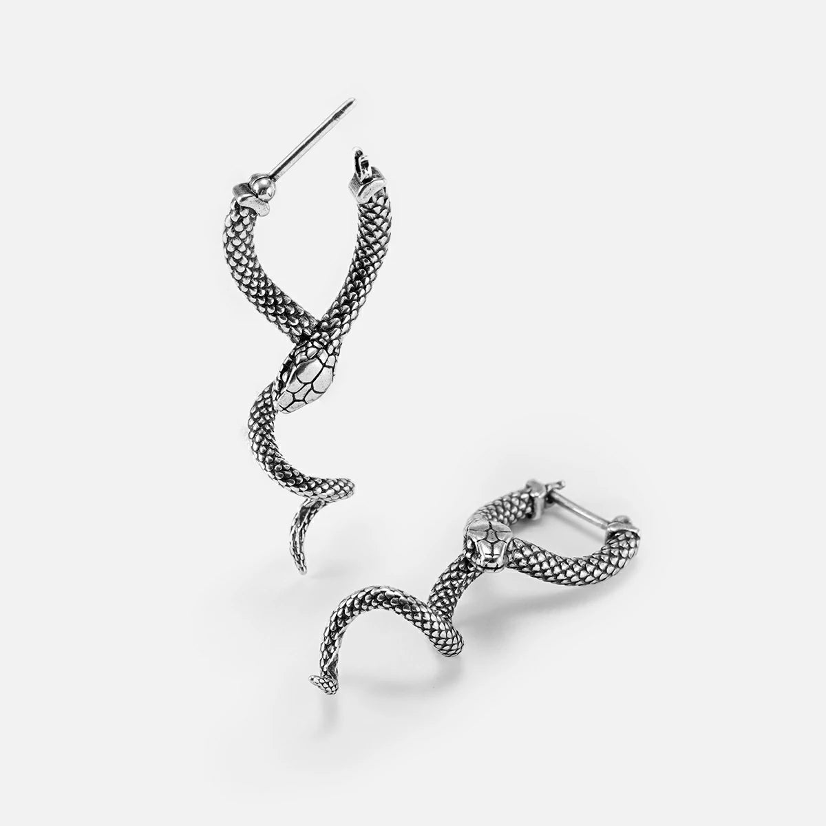 Pair of silver-tone serpent earrings with scale texture shown at an angle on a plain background
