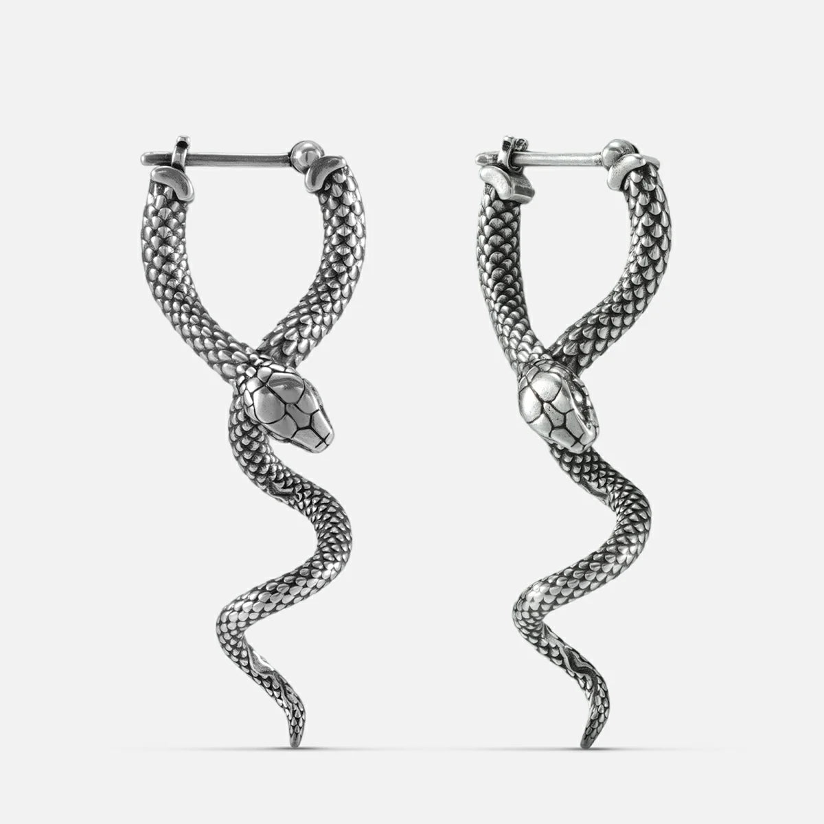 Pair of oxidized silver-tone earrings shaped like coiled serpents with textured scale detail, front view
