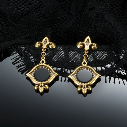 Gold-tone Silent Lens Drop Earrings displayed as a pair against black lace on a dark reflective surface.