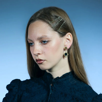 Gold-tone Silent Lens Drop Earrings worn in a downward-looking portrait, highlighting the suspended eye-shaped frames.
