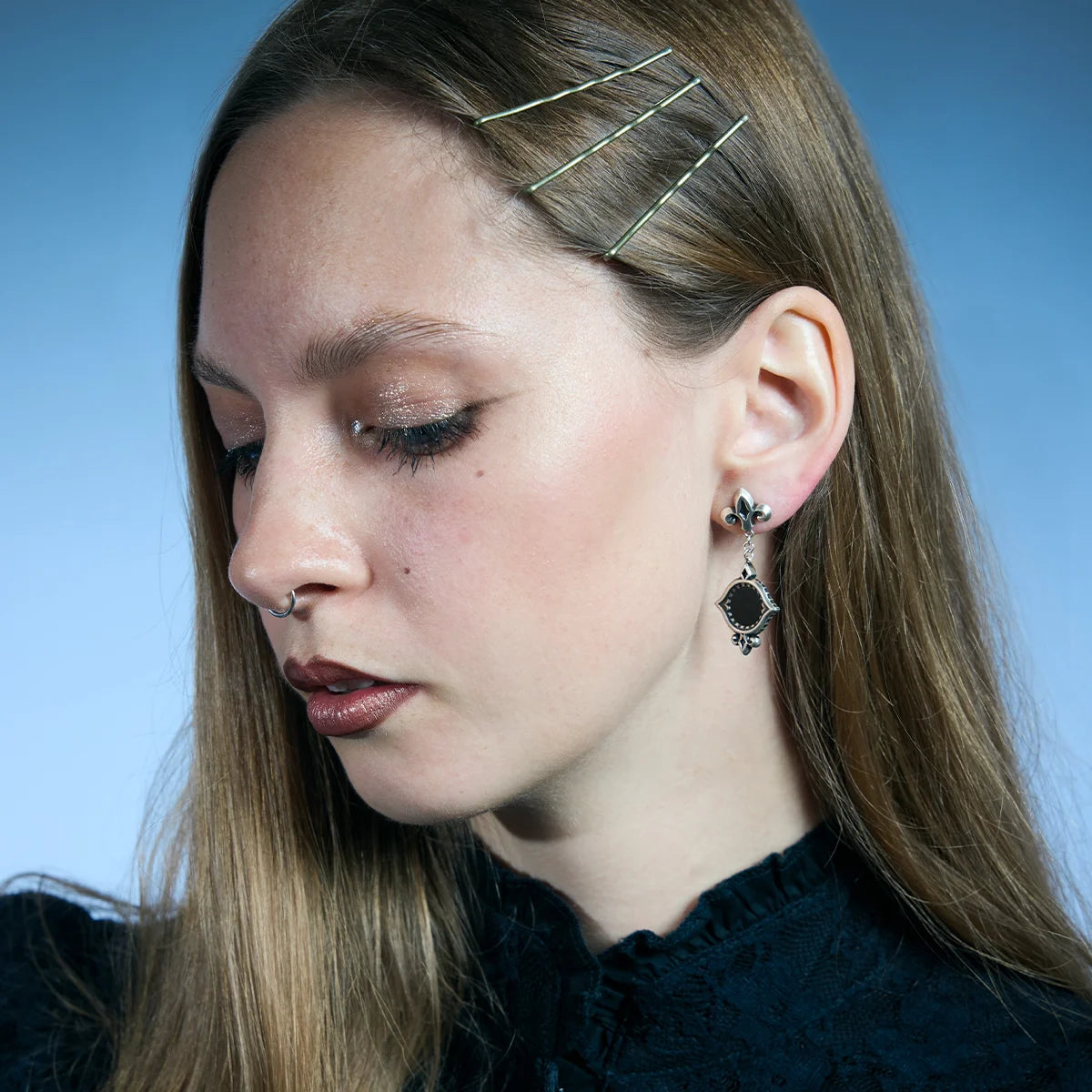 Antiqued silver-tone Silent Lens Drop Earrings worn in a downward-looking portrait, highlighting the black obsidian centers.